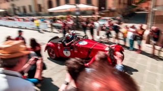 A picture of a classic car and the cheering crowd during the 1000 Miglia event 