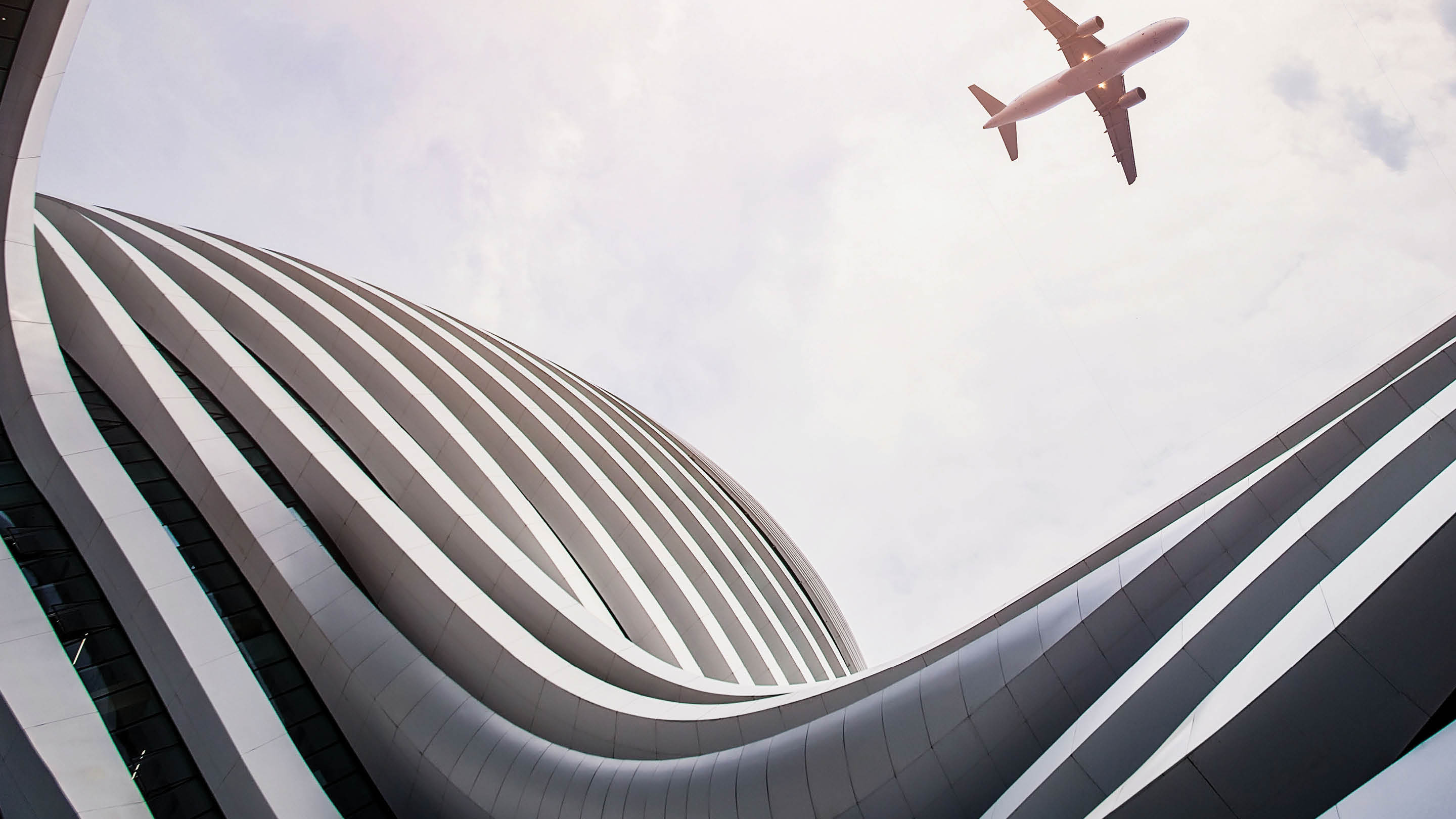 Photograph of an airplane soaring over a building.