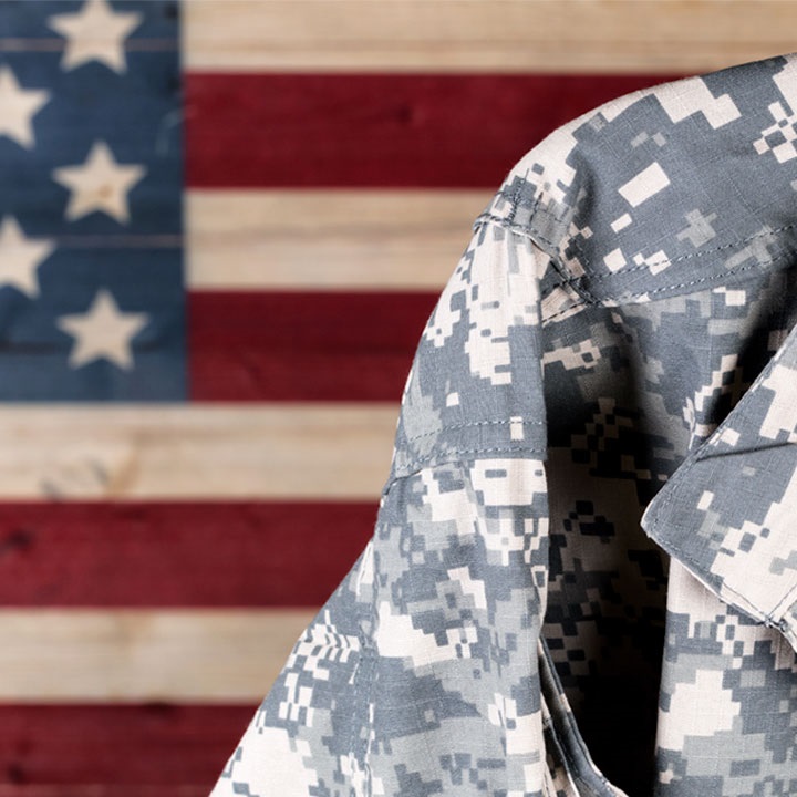 Photo of someone wearing a digital camouflage ACU in front of the American flag.